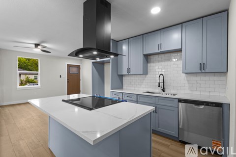 A modern kitchen with a large island and a stainless steel range hood.