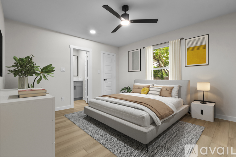 A bedroom with a large bed, a ceiling fan, and a plant on a nightstand.