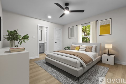 A bedroom with a large bed, a ceiling fan, and a plant on a nightstand.