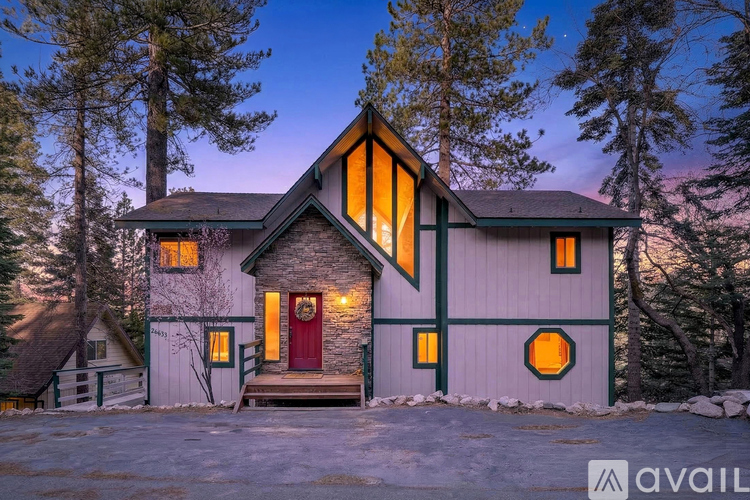 A house with a red door stands in front of a forest.