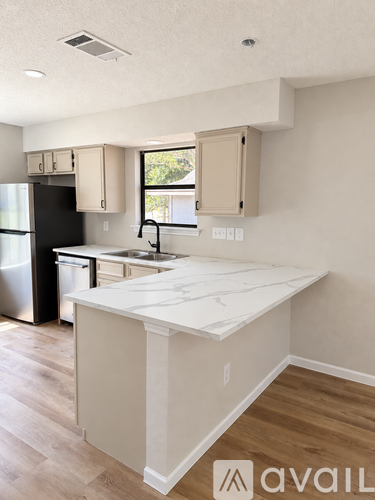 A kitchen with a white counter top and wooden floors.