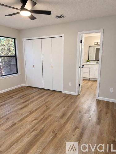 A room with a ceiling fan and wooden flooring.