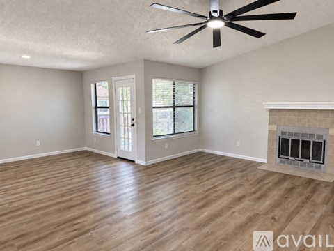 A spacious room with a fireplace and a ceiling fan.