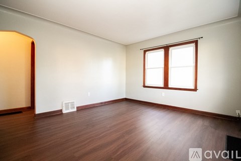 A room with wooden floors and a window with blinds.