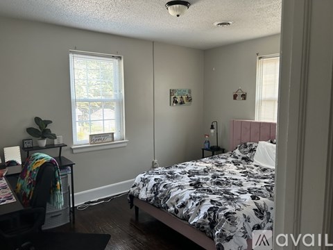 A bedroom with a bed, a desk, and a window.