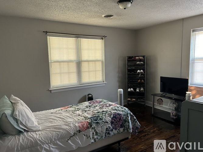 A bedroom with a bed, a television, and a shelf with shoes.