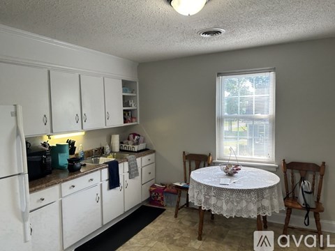 A kitchen with white cabinets and a table with a white lace tablecloth.
