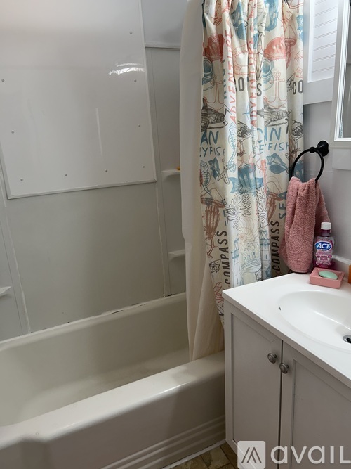 A white bathroom with a shower curtain and a towel hanging on a hook.