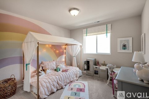 A child's bedroom with a canopy bed and a rainbow-colored wall.