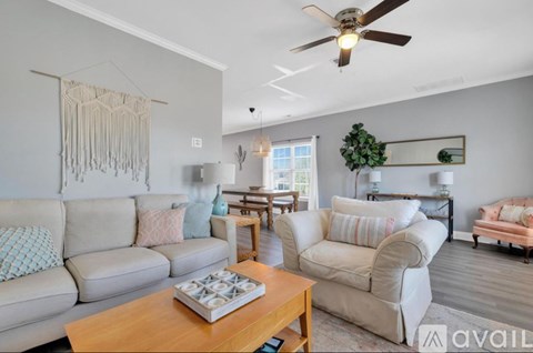 A living room with a beige couch, a wooden coffee table, and a ceiling fan.