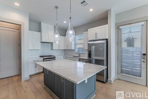 A modern kitchen with a large island and stainless steel appliances.