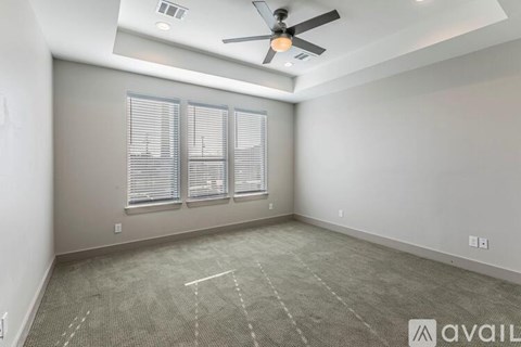 A spacious room with a ceiling fan and carpeted floor.