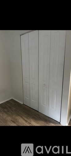 A white wardrobe with four doors is in a room with wooden flooring.