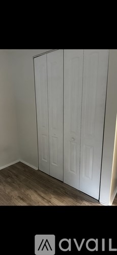 A white wardrobe with four doors is in a room with wooden flooring.