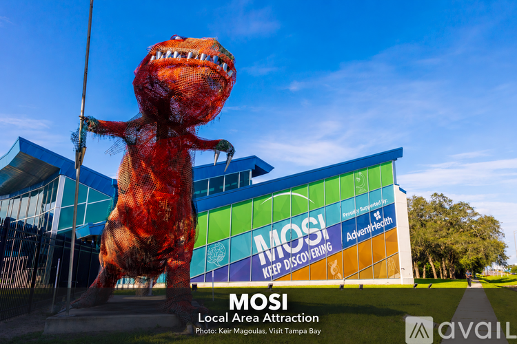 A dinosaur statue stands in front of a building with the sign "MOSI Local Area Attraction.".