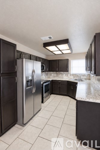 A kitchen with black cabinets and a stainless steel refrigerator.