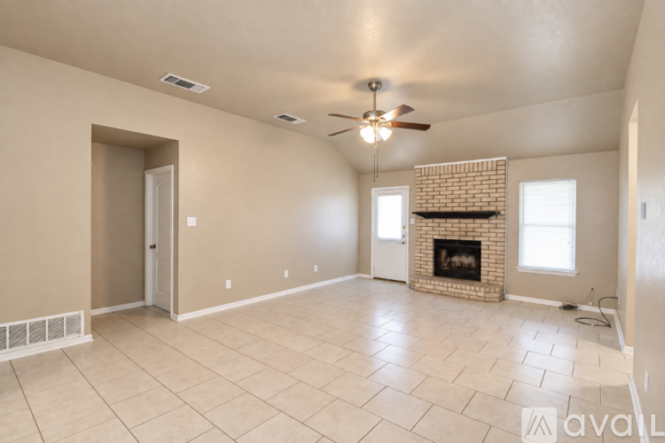 A spacious living room with a fireplace and a ceiling fan.