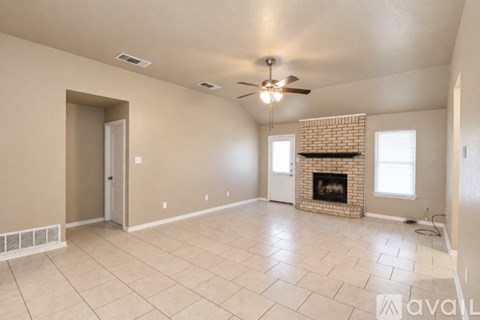 A spacious living room with a fireplace and a ceiling fan.