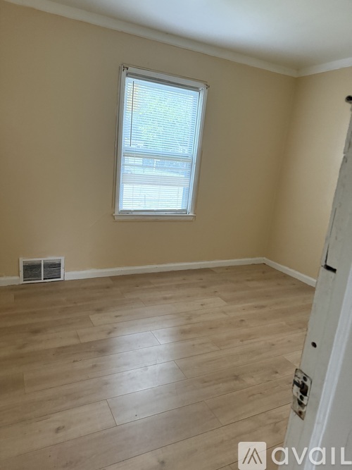 A room with a window and wooden flooring.