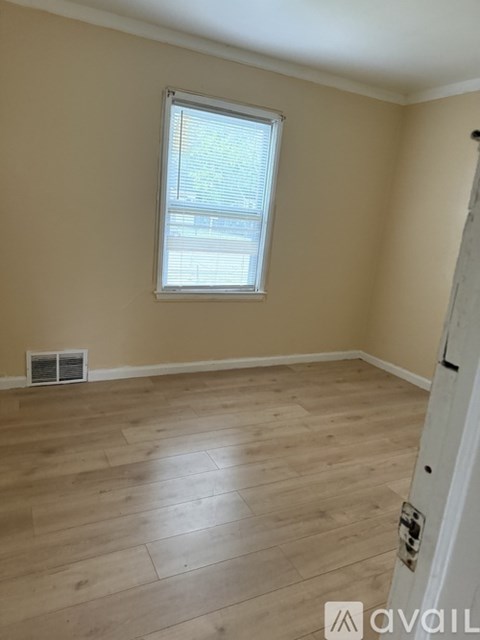 A room with a window and wooden flooring.