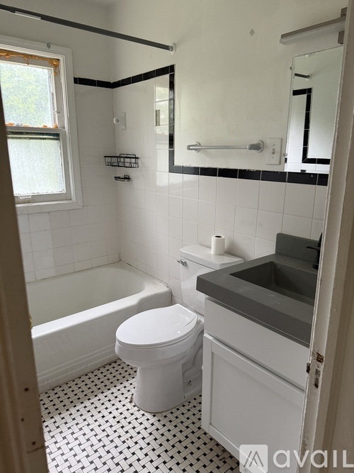 A white toilet sits in a bathroom with black and white tiles.