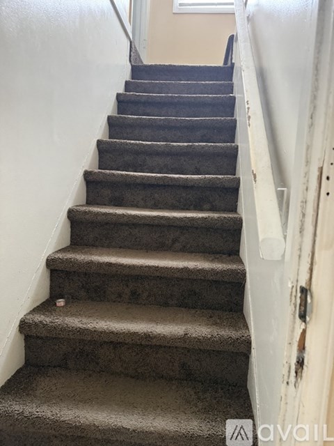 A staircase with a carpeted runner and a white door on the right side.