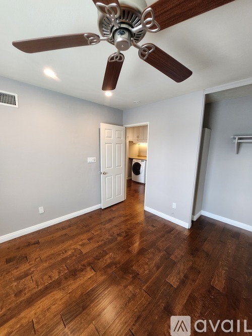 A room with a ceiling fan and wooden flooring.