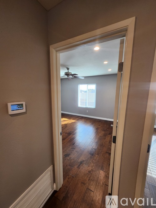 A room with a doorway leading to another room with a ceiling fan.
