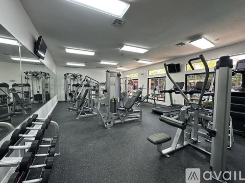 A gym with a variety of equipment including treadmills, weights, and exercise machines.