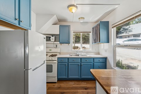 A kitchen with blue cabinets and a white refrigerator.