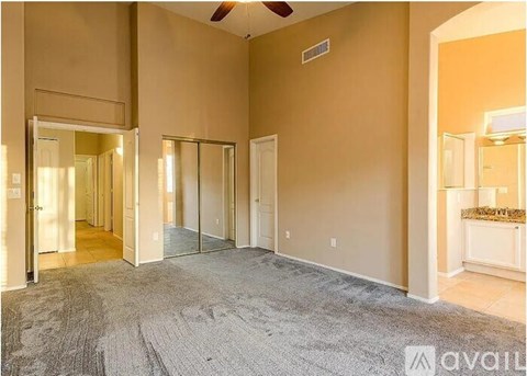 A spacious room with a carpeted floor and a ceiling fan.