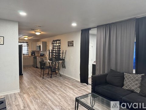 A living room with a black couch and a glass coffee table.