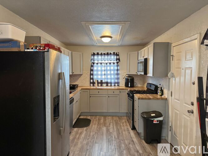 A kitchen with a black refrigerator and wooden floors.