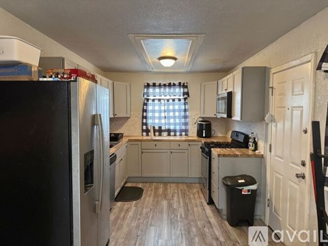 A kitchen with a black refrigerator and wooden floors.
