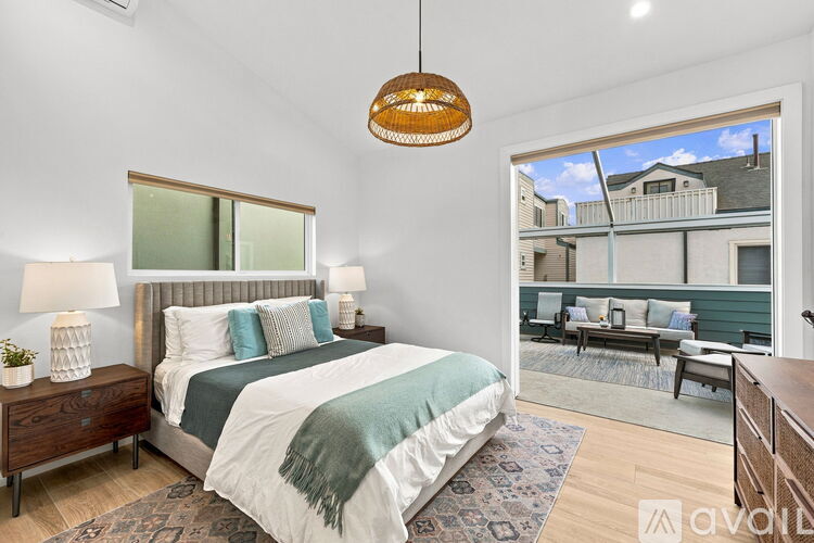A bedroom with a large bed and a view of a balcony with furniture.