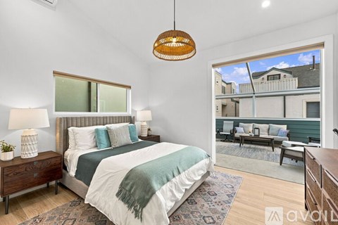 A bedroom with a large bed and a view of a balcony with furniture.
