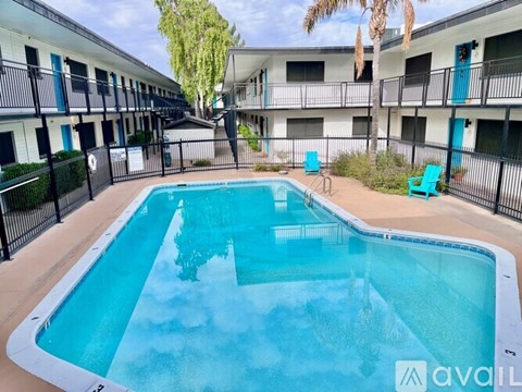 A swimming pool surrounded by a black fence and blue chairs.