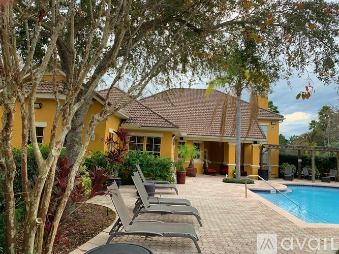 A yellow house with a pool and lounge chairs.