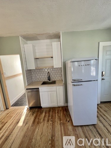 A white Galanz refrigerator stands in a kitchen with wood flooring.