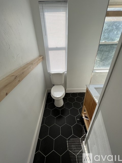 A bathroom with a toilet, hexagonal tiles, and a window.