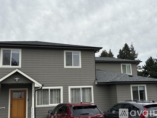 A grey house with a red car parked in front.