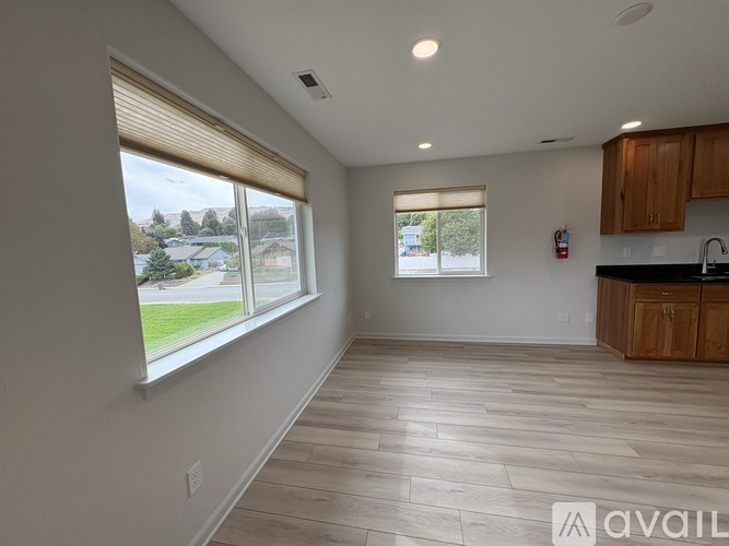 A spacious room with wooden flooring and large windows.