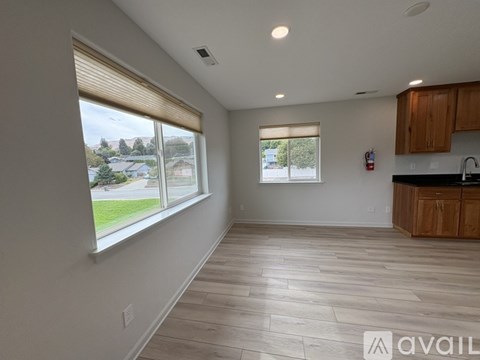 A spacious room with wooden flooring and large windows.