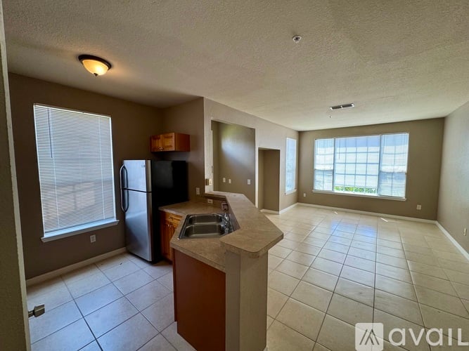 A kitchen with a refrigerator, sink, and cabinets.