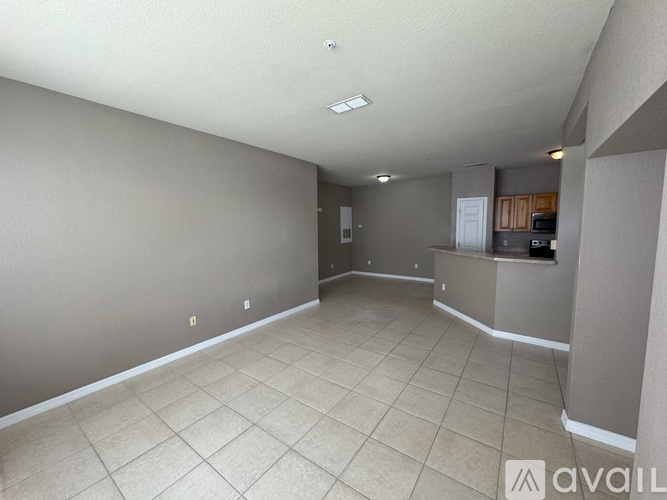 A spacious room with beige tiled flooring and white walls.