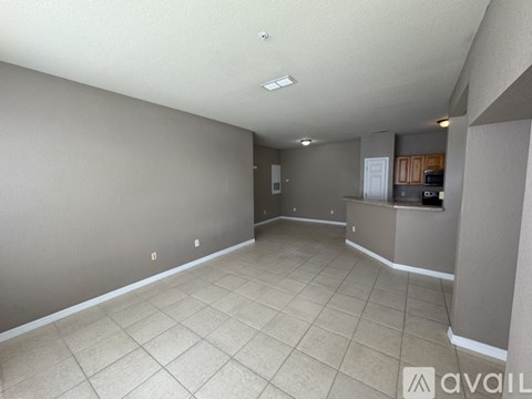 A spacious room with beige tiled flooring and white walls.