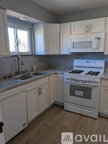 A kitchen with white cabinets and appliances.