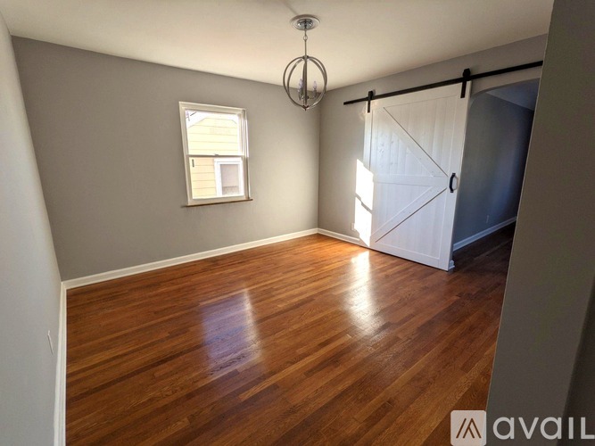A room with wooden flooring and a window with blinds.