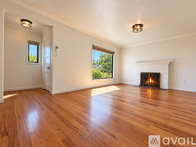 A spacious room with a fireplace and wooden flooring.
