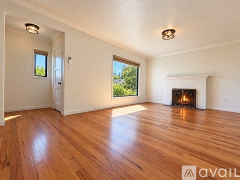 A spacious room with a fireplace and wooden flooring.